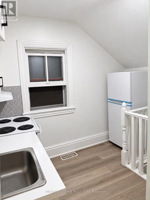 A small kitchen with a sink, stove, and a window.