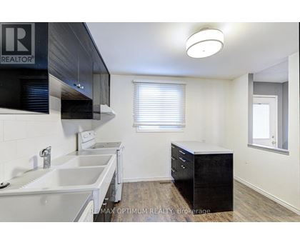 A kitchen with white countertops and a black cabinet.