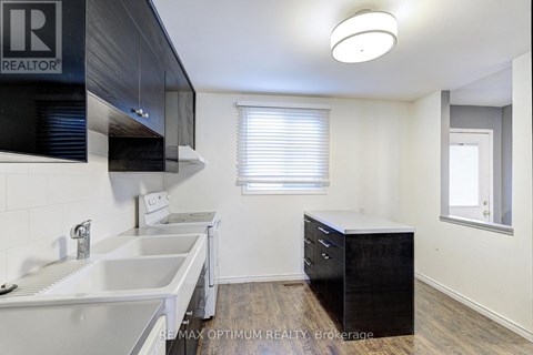 A kitchen with white countertops and a black cabinet.