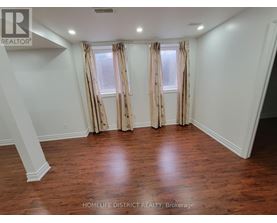 A room with wooden floors and a window with curtains.