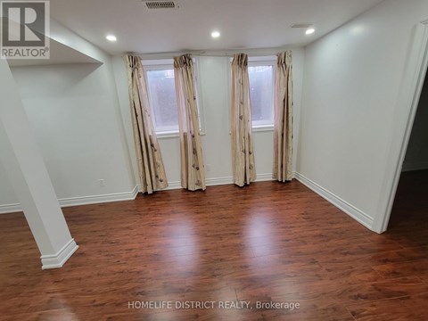 A room with wooden floors and a window with curtains.