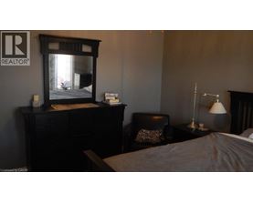 A bedroom with a bed, chair, and lamp.