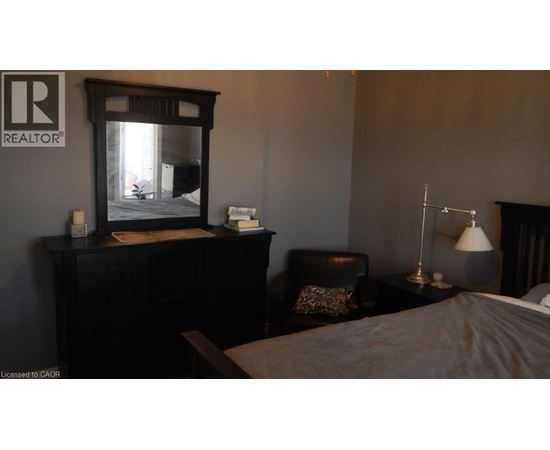 A bedroom with a bed, chair, and lamp.