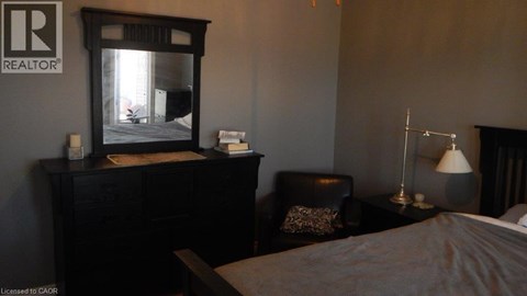 A bedroom with a bed, chair, and lamp.