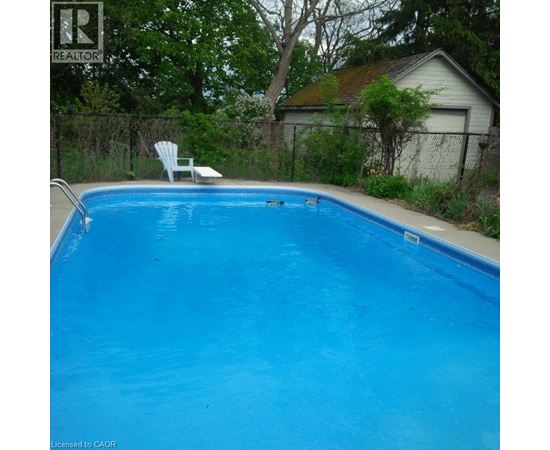 A blue swimming pool with a white chair by the side.