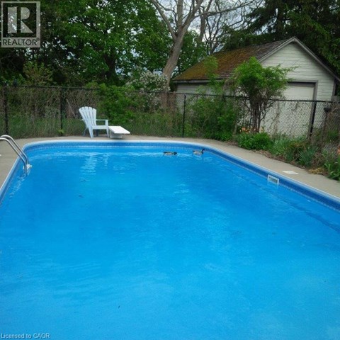 A blue swimming pool with a white chair by the side.