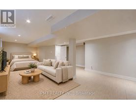 A well-lit, spacious living room with a sofa, bed, and television.