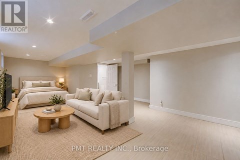 A well-lit, spacious living room with a sofa, bed, and television.