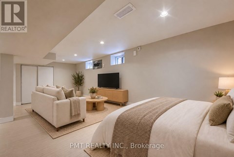 A well-lit bedroom with a large bed and a flat-screen TV.