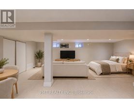 A well-lit bedroom with a large bed and a flat-screen TV mounted on the wall.