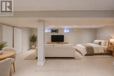 A well-lit bedroom with a large bed and a flat-screen TV mounted on the wall.
