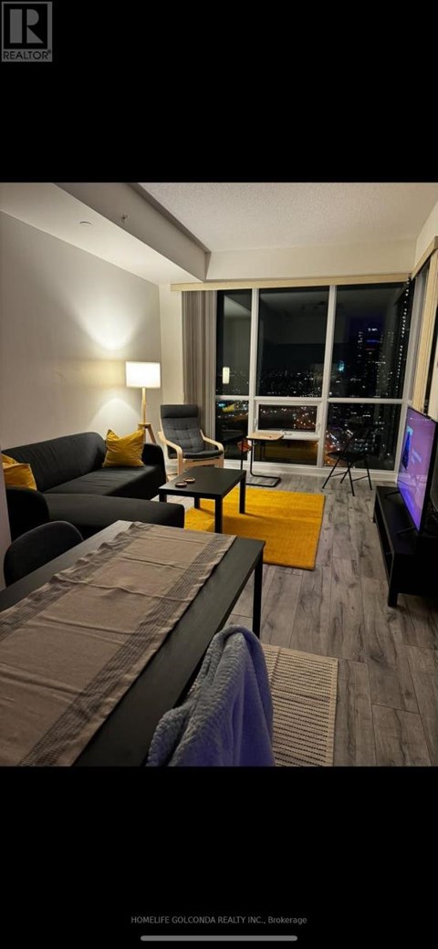 A modern living room with a black couch and a large window overlooking the city.