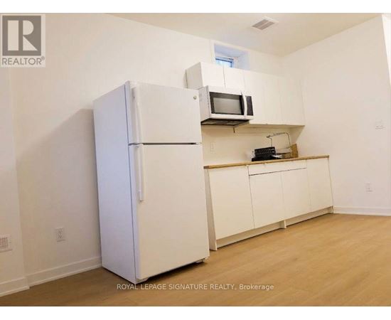A white refrigerator is in a kitchen with a microwave above it.