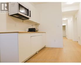 A kitchen with a white fridge and a microwave above it.