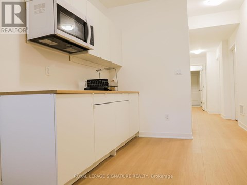 A kitchen with a white fridge and a microwave above it.