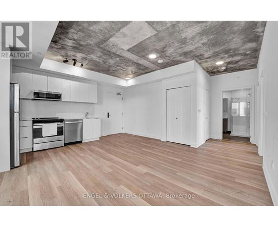 A spacious kitchen with wooden flooring and a ceiling with exposed beams.