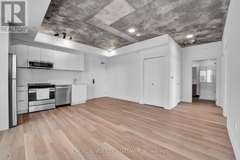 A spacious kitchen with wooden flooring and a ceiling with exposed beams.