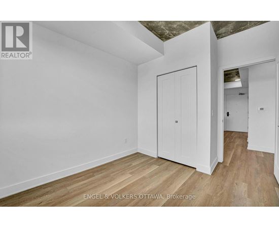 A white room with wooden floors and a door on the left.