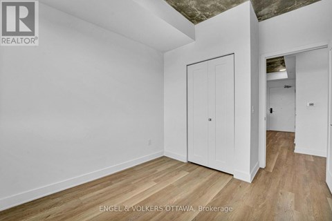 A white room with wooden floors and a door on the left.