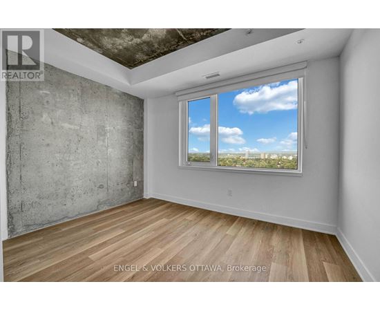A room with a large window showing a view of the sky and trees.