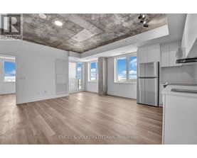 A spacious, empty room with wooden floors and a concrete ceiling.