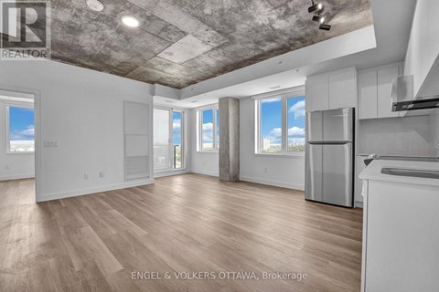 A spacious, empty room with wooden floors and a concrete ceiling.