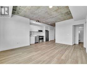 A large empty room with wooden floors and a concrete ceiling.