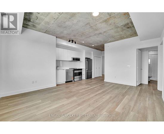 A large empty room with wooden floors and a concrete ceiling.