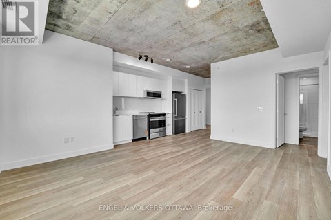 A large empty room with wooden floors and a concrete ceiling.