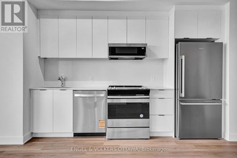 A modern kitchen with white cabinets and stainless steel appliances.