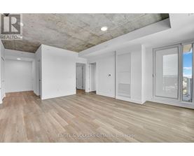 A spacious room with wooden flooring and white walls.