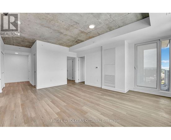 A spacious room with wooden flooring and white walls.