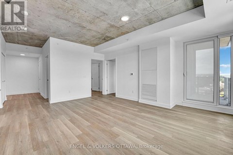 A spacious room with wooden flooring and white walls.
