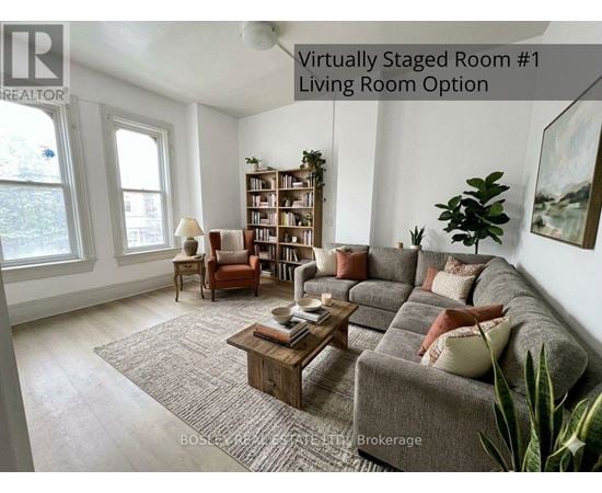 A living room with a grey couch, a wooden coffee table, a bookshelf, and a potted plant.