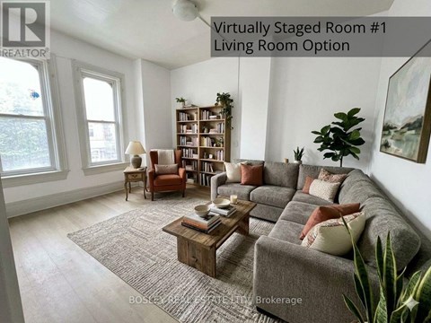 A living room with a grey couch, a wooden coffee table, a bookshelf, and a potted plant.