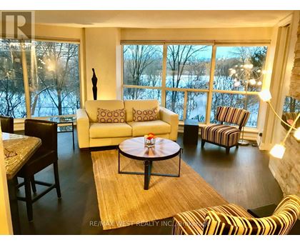 A living room with a large window and a view of trees and water outside.