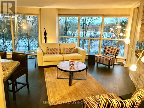 A living room with a large window and a view of trees and water outside.