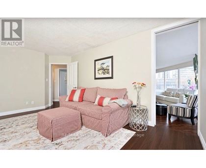 A living room with a pink couch and a painting on the wall.
