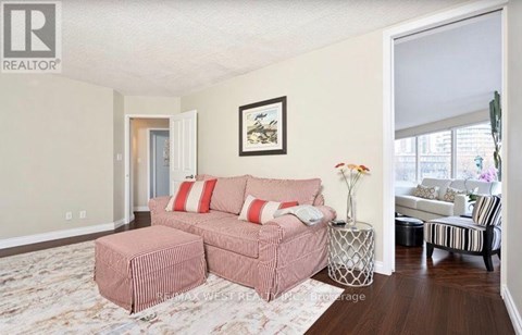 A living room with a pink couch and a painting on the wall.