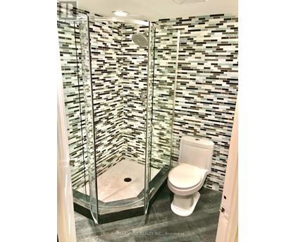 A white toilet in a bathroom with a glass shower stall.