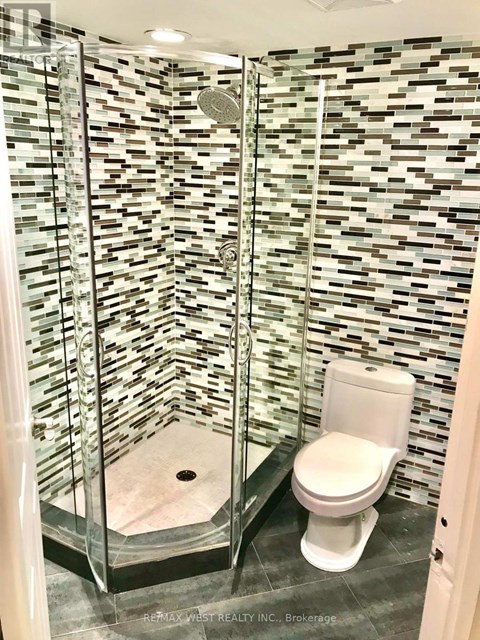 A white toilet in a bathroom with a glass shower stall.