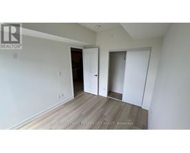A room with white walls and wooden flooring, with a door on the left and a closet on the right.