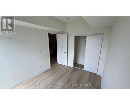 A room with white walls and wooden flooring, with a door on the left and a closet on the right.