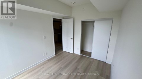 A room with white walls and wooden flooring, with a door on the left and a closet on the right.