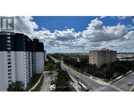 A view of a city street from a high vantage point with buildings on either side and cars driving on the road.