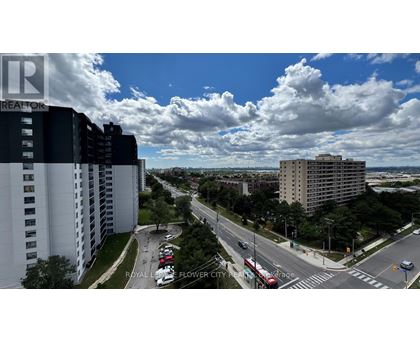 A view of a city street from a high vantage point with buildings on either side and cars driving on the road.