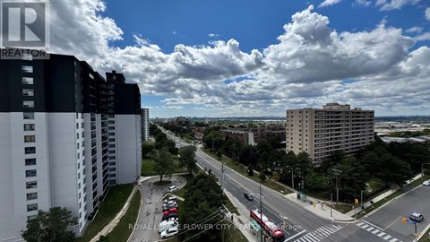 A view of a city street from a high vantage point with buildings on either side and cars driving on the road.