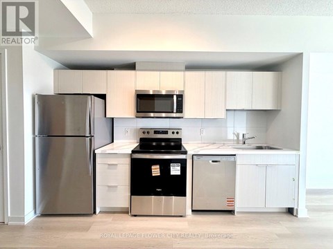 A kitchen with a refrigerator, oven, and microwave.