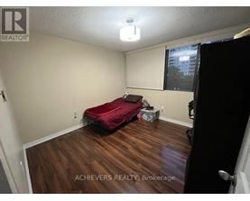A bedroom with a red bed and wooden floors.