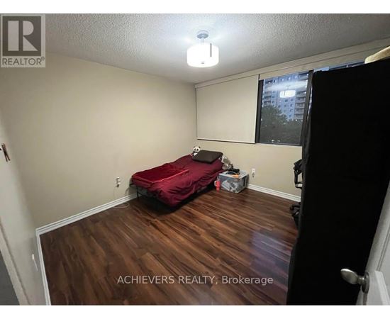 A bedroom with a red bed and wooden floors.